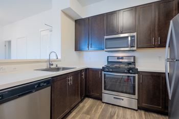 A kitchen with dark wood cabinets and stainless steel appliances